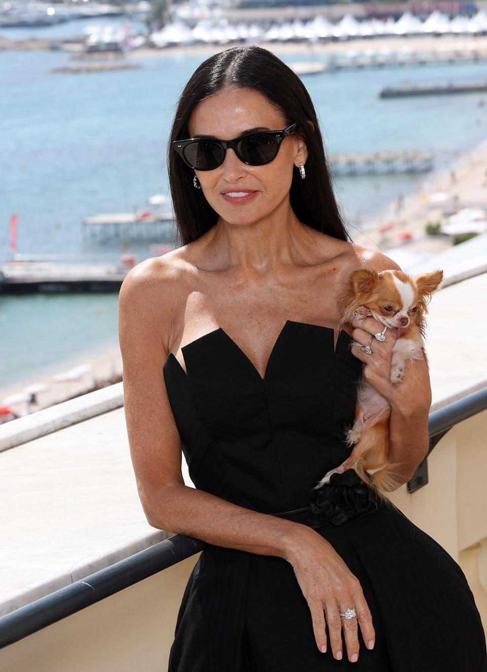 Demi Moore wearing a black strapless dress holding her dog