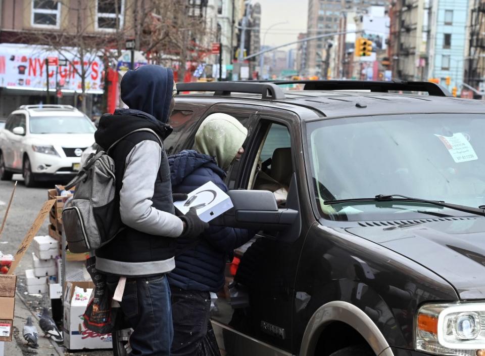 Peddlers unsuccessfully try to sell the phony merch to a passing motorist on Canal Street. Helayne Seidman