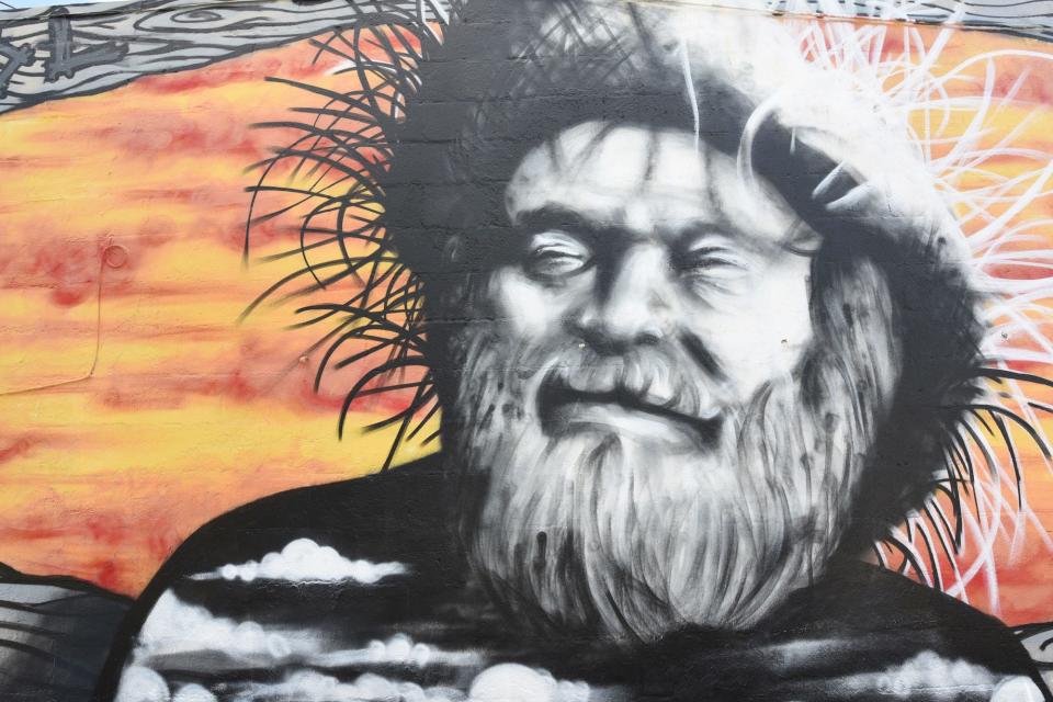 Travelers en route to Fort Fisher won’t easily miss this roadside  portrait of its famous hermit, bordered by the words “School of Common Sense,” a mantra of the local legend. The mural was a personal project for Wilmington artist Rob Fogle, who painted the hermit on the back of the Last Resort bar in Carolina Beach in 2015. It predates the Carolina Beach Mural Project, which began in 2020.