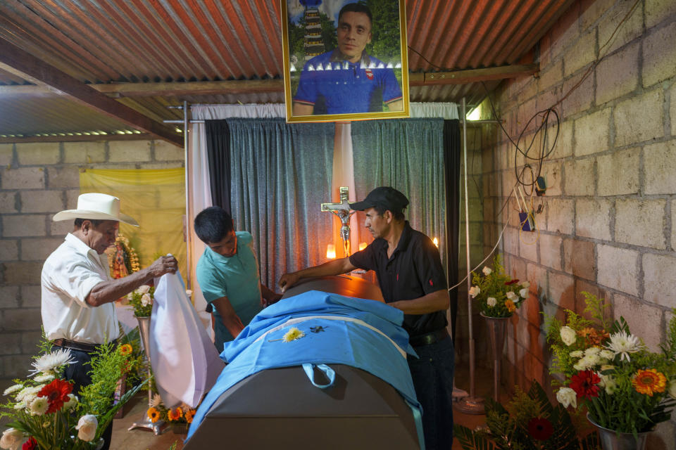 Familiares colocan una bandera de Guatemala sobre el ataúd de Miguel Rojché en su velorio en su casa en Chicacao, Guatemala, el miércoles 12 de abril de 2023. Rojché y su tío Miguel murieron en un incendio cuando estaba encerrados en un centro de detención de migrantes mexicano en Ciudad Juárez. (AP Foto/Moisés Castillo)