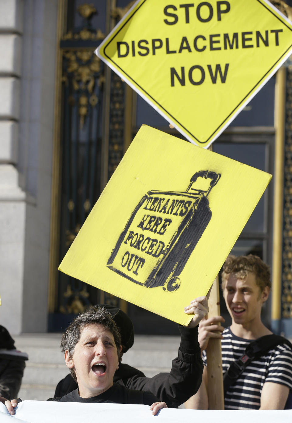 Sara Shortt of the Housing Rights Committee of San Francisco yells during a protest outside of City Hall in San Francisco, Tuesday, Jan. 21, 2014. San Francisco officials are set to vote on a plan to start regulating employee shuttles for companies like Google, Facebook and Apple, charging a fee for those that use public bus stops and controlling where they load and unload. Private shuttle buses have created traffic problems, blocking public bus stops during peak commute hours. (AP Photo/Jeff Chiu)