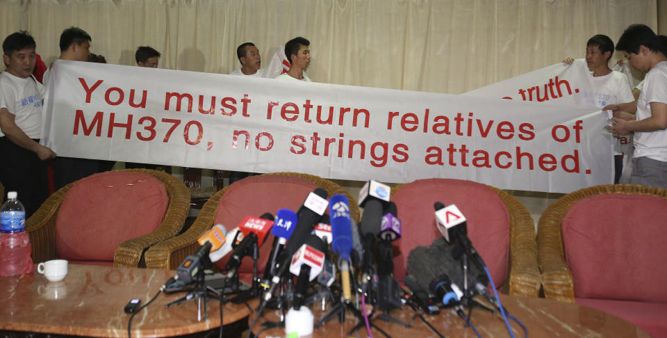 Newly arrived Chinese relatives of passengers on board the missing Malaysia Airlines flight MH370 hold a sign as they speak to reporters at a hotel in Subang Jaya, Malaysia, Sunday March 30, 2014. Several dozen Chinese relatives of passengers on Flight 370 arrived in Malaysia Sunday to demand more information about what happened to the airliner that has been missing for more than three weeks, saying there has not been enough information on what happened to their loved ones. (AP Photo/Aaron Favila)