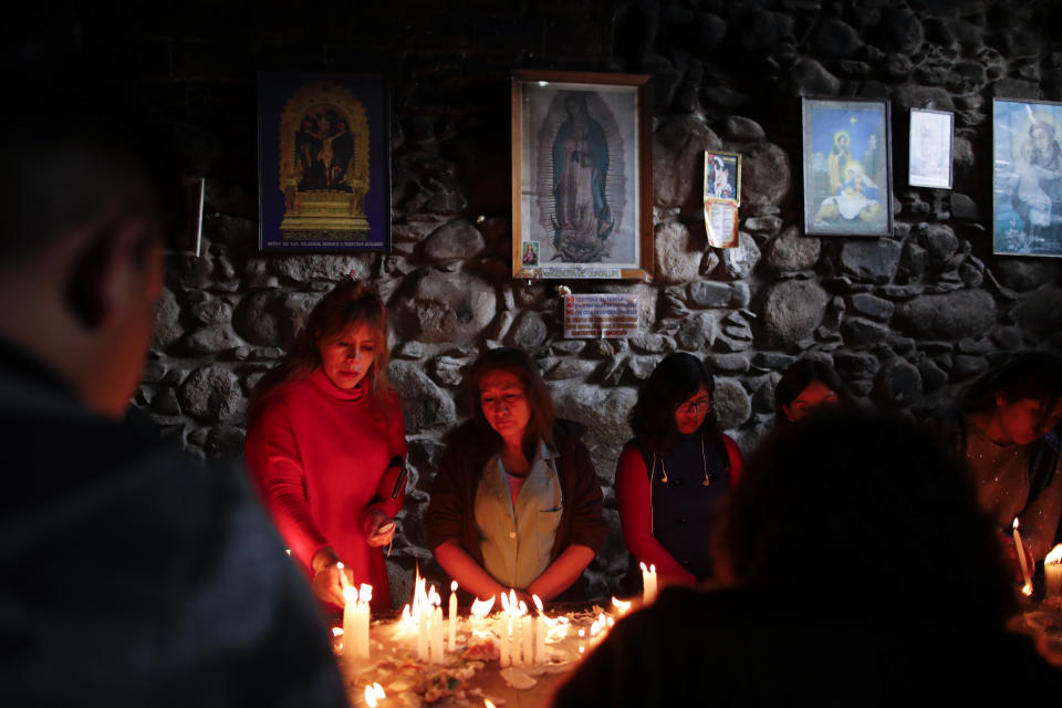 In this picture taken Monday, Jan. 6, 2020, people light candles inside the San Francisco Church during a Catholic Mass for Three Kings Day in La Paz, Bolivia. Outside the church, many parishioners flocked to indigenous guides to get additional blessings that come from the ancestral indigenous beliefs in the Pachamama, or mother earth deity. (AP Photo/Natacha Pisarenko)