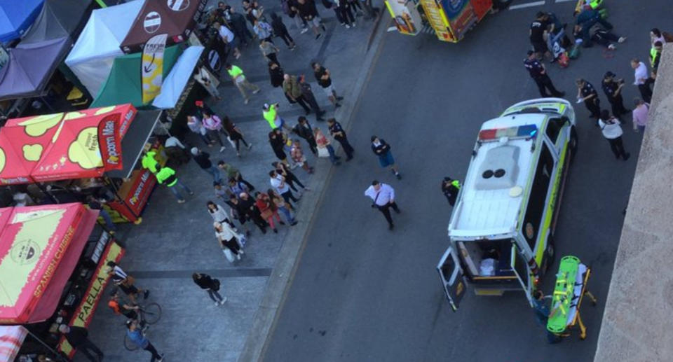 An ambulance and groups of people gather after three pedestrians hit by car in George Street, Brisbane.