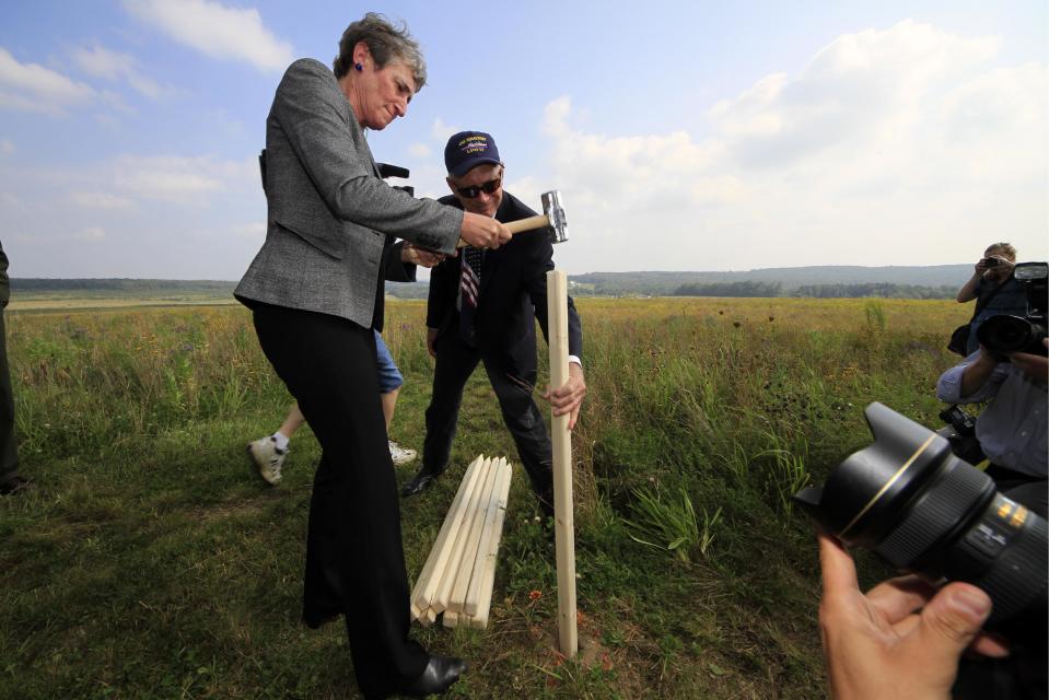 Secretary of the Interior Sally Jewell, left, pounds a stake held by Patrick White, vice president of the Families of Flight 93, into the ground as part of a ground breaking ceremony for the Flight 93 National Memorial visitor center complex on Tuesday, Sept. 10, 2013, in Shanksville, Pa. The 450-foot-long visitors center is scheduled to be opened in late 2015. (AP Photo/Gene J. Puskar)