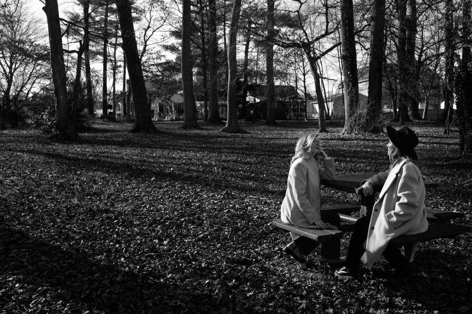 a couple of women sitting on a bench in a park