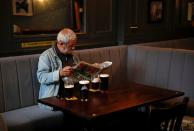 A man reads a newspaper as he sits inside the Grapes pub in Liverpool