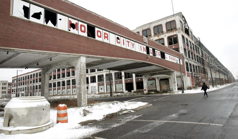 A woman walks next to the abandoned Packard Motor Car Company building, that ceased production in the 1950’s, in Detroit, Mich., in 2008.