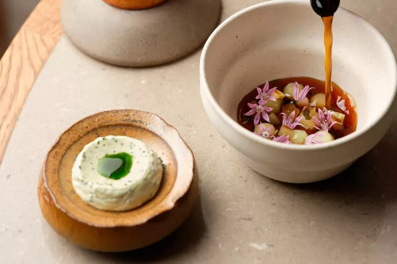 Broth of grilled onions with jersey royals cooked in aromats, and pickled garlic served at Skof in Manchester