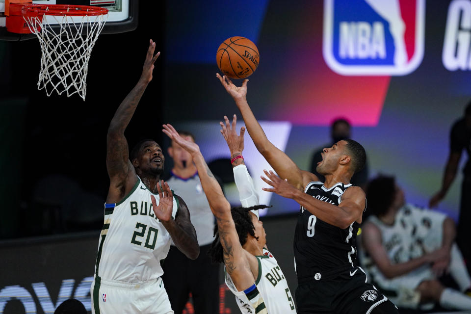 Brooklyn Nets guard Timothe Luwawu-Cabarrot (9) shoots over Milwaukee Bucks forward Marvin Williams (20) and forward D.J. Wilson (5) during the second half of an NBA basketball game Tuesday, Aug. 4, 2020 in Lake Buena Vista, Fla. (AP Photo/Ashley Landis)