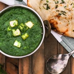 A bowl of palak paneer which is essentially cottage cheese in a spinach based sauce, and served with naan