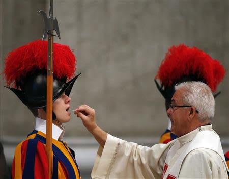 A Swiss Guard receives holy communion as Pope Francis leads Chrism mass in Saint Peter's Basilica at the Vatican April 17, 2014. REUTERS/Stefano Rellandini