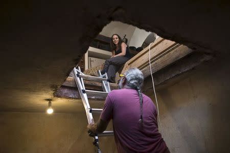 Ein Karem resident Uria (top) watches as her husband Tal climbs down a ladder into a ritual bath that was discovered under their house in Jerusalem, July 1, 2015. REUTERS/Ronen Zvulun