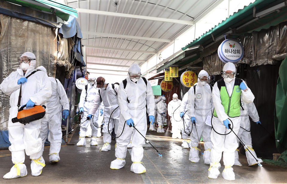 Workers wearing protective suits spray disinfectant as a precaution against the coronavirus at a market in Bupyeong, South Korea, Monday, Feb. 24, 2020. South Korea reported another large jump in new virus cases Monday a day after the the president called for "unprecedented, powerful" steps to combat the outbreak that is increasingly confounding attempts to stop the spread. (Lee Jong-chul/Newsis via AP)