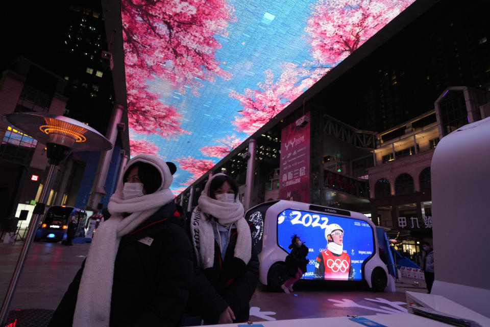 Promoters at an event organized by sponsors of the 2022 Winter Olympics wait for visitors at a mall in Beijing on Thursday, Feb. 10, 2022. The possibility of a large outbreak in the bubble, potentially sidelining athletes from competitions, has been a greater fear than any leakage into the rest of China. (AP Photo/Ng Han Guan)