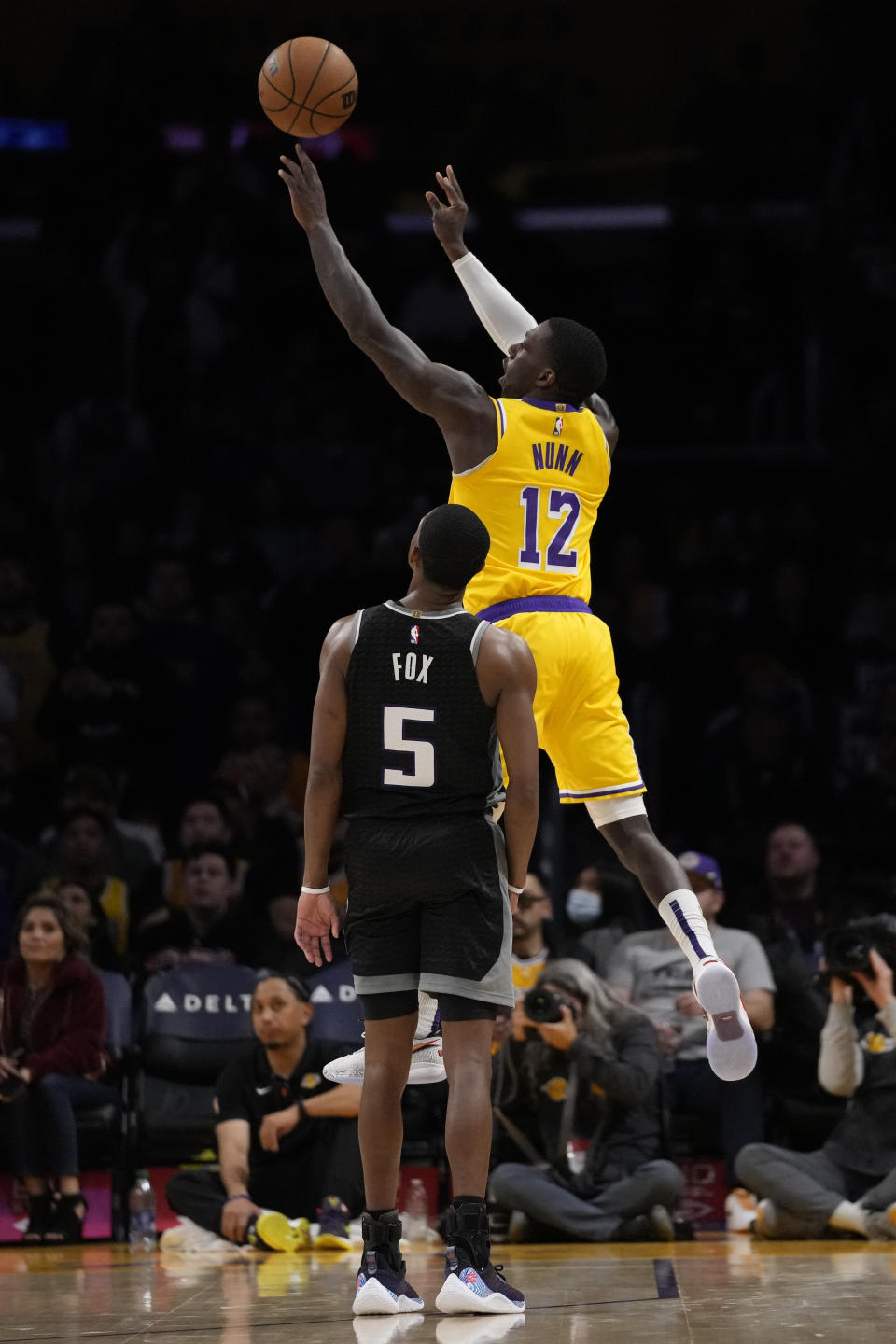 Los Angeles Lakers guard Kendrick Nunn (12) shoots a 3-pointer against Sacramento Kings guard De'Aaron Fox (5) during the second half of an NBA basketball game in Los Angeles, Wednesday, Jan. 18, 2023. (AP Photo/Ashley Landis)