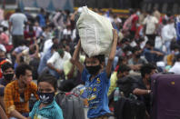 Children of migrant workers from other states wait outside a railway station to catch a train to return to their hometowns, in Mumbai, India, Friday, May 15, 2020. The pandemic has exposed India's deep economic divide as millions of migrant workers have left Indian cities with luggage bags perched on their heads and children in their arms, walking down highways in desperate attempts to reach the countryside. (AP Photo/Rafiq Maqbool)