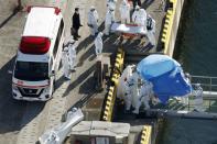 Officers in protective gear escort a person who was on board cruise ship Diamond Princess and was tested positive for coronavirus, after the person is transferred to a maritime police base in Yokohama