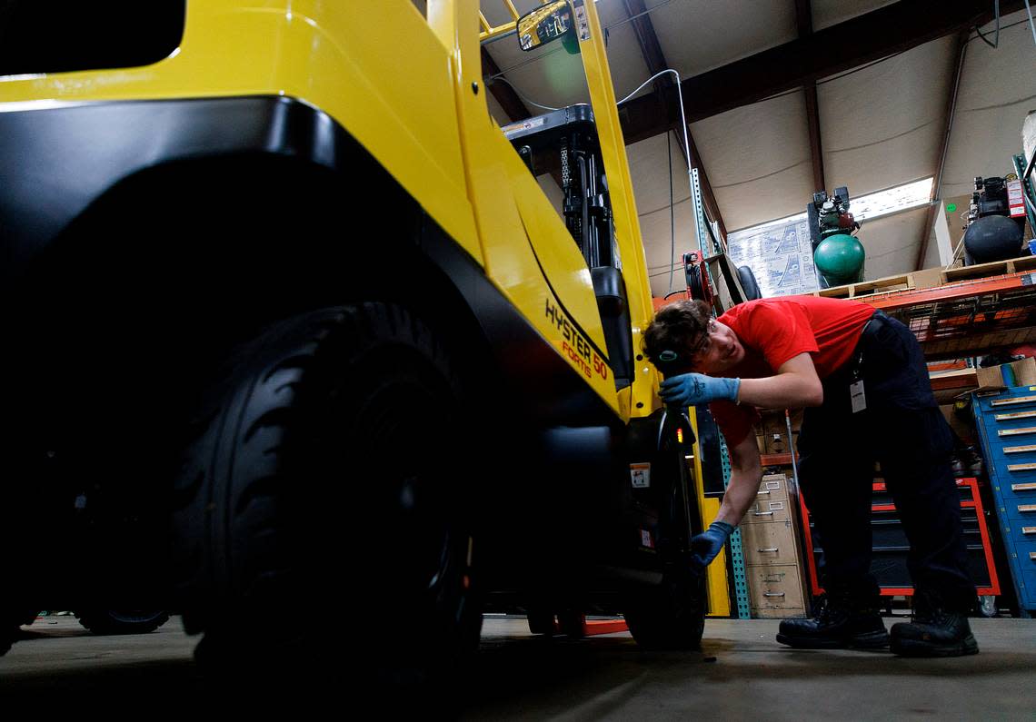 Wake Technical Community College student Dominic Cavallini tightens the wheel fasteners on a forklift in the shop at The Gregory Poole Equipment Company in Raleigh.