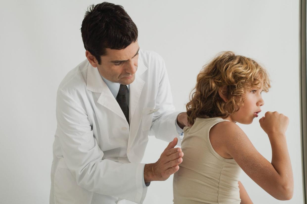 Doctor checking young patient's cough