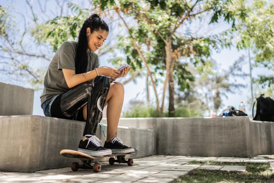 A woman sitting on a step with here feet on a skateboard.