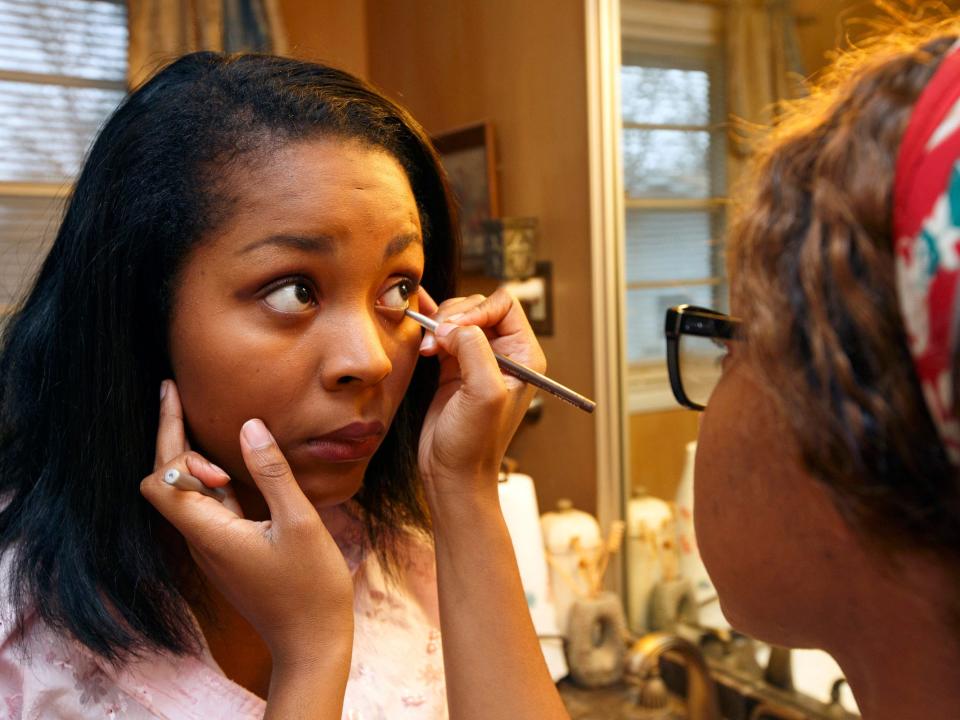 woman applies eyeliner to another womans eye