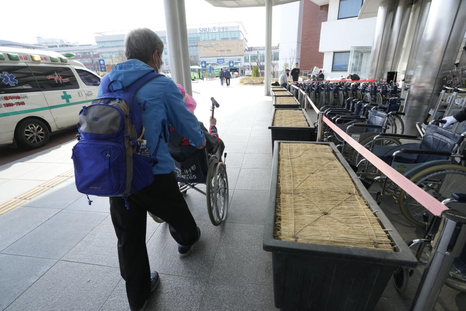 A patient in a wheelchair and her guardian leave Seoul National University Hospital in Seoul, South Korea, Monday, April 1, 2024. South Korea's President Yoon Suk Yeol vowed Monday not to back down in the face of vehement protests by doctors seeking to derail his plan to drastically increase medical school admissions, as he called their walkouts "an illegal collective action" that poses "a grave threat to our society." (AP Photo/Ahn Young-joon)