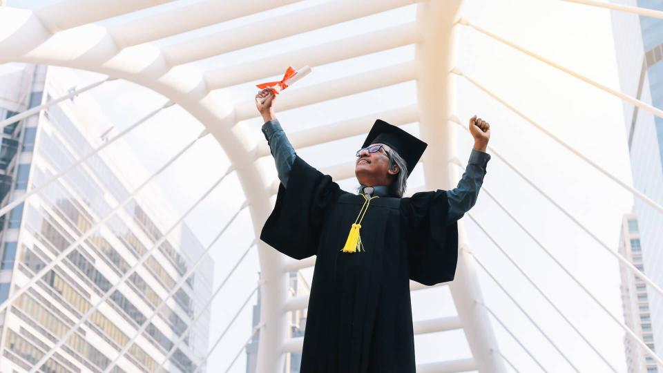 Happy senior adult man in a hat  with his gown on graduation day.