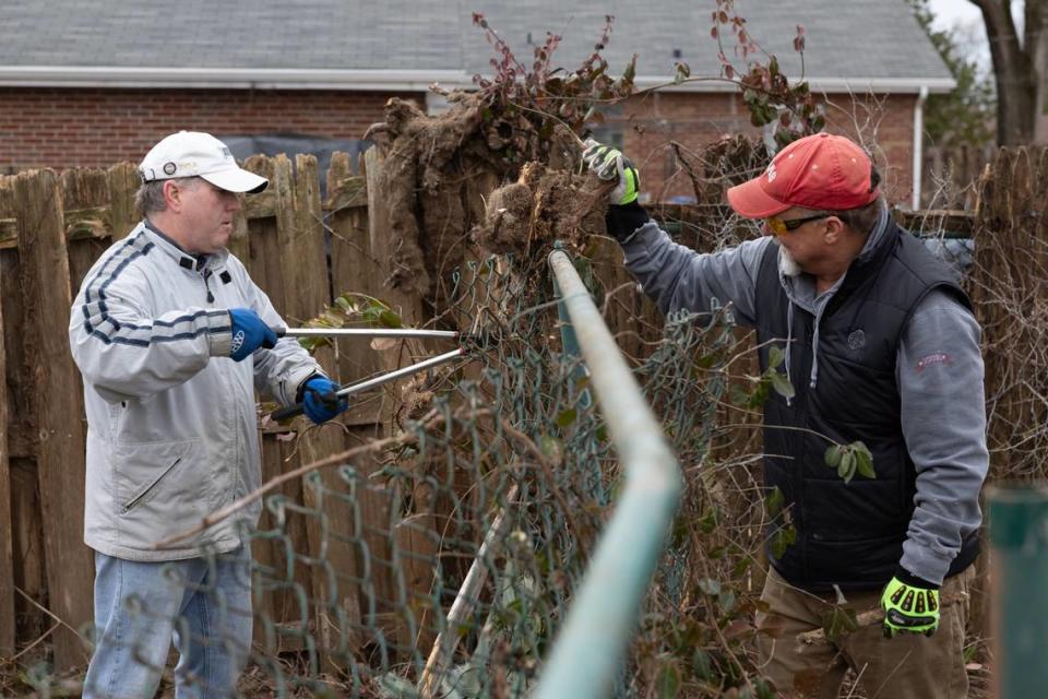 Brian Dumstorff, left, and Chad Rollins, volunteers with West End Redevelopment Corp., work on removing a fence behind a home at 300 S. 74th St. in Belleville that is being renovated.
