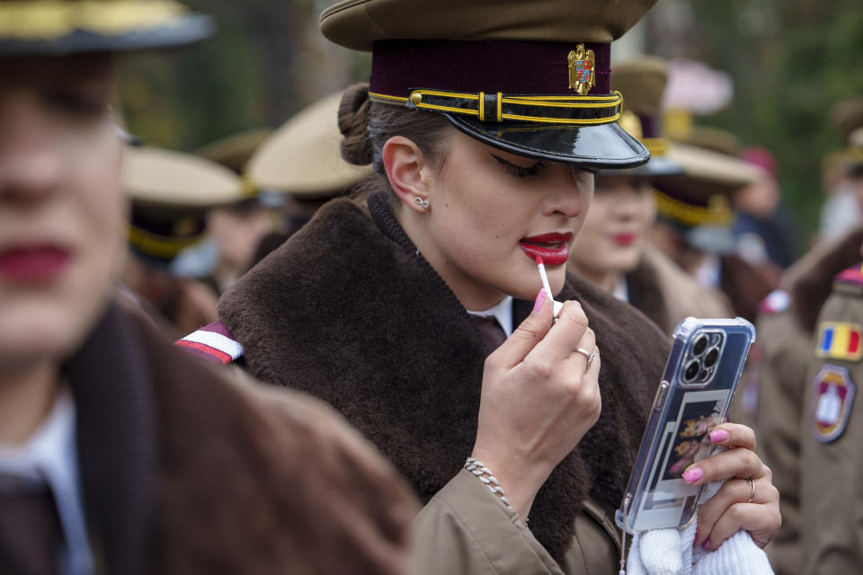 A military cadet refreshes her lipstick before the National Day parade in Bucharest, Romania, Friday, Dec. 1, 2023. Tens of thousands of people turned out in Romania's capital on Friday to watch a military parade that included troops from NATO allies to mark the country's National Day. (AP Photo/Vadim Ghirda)