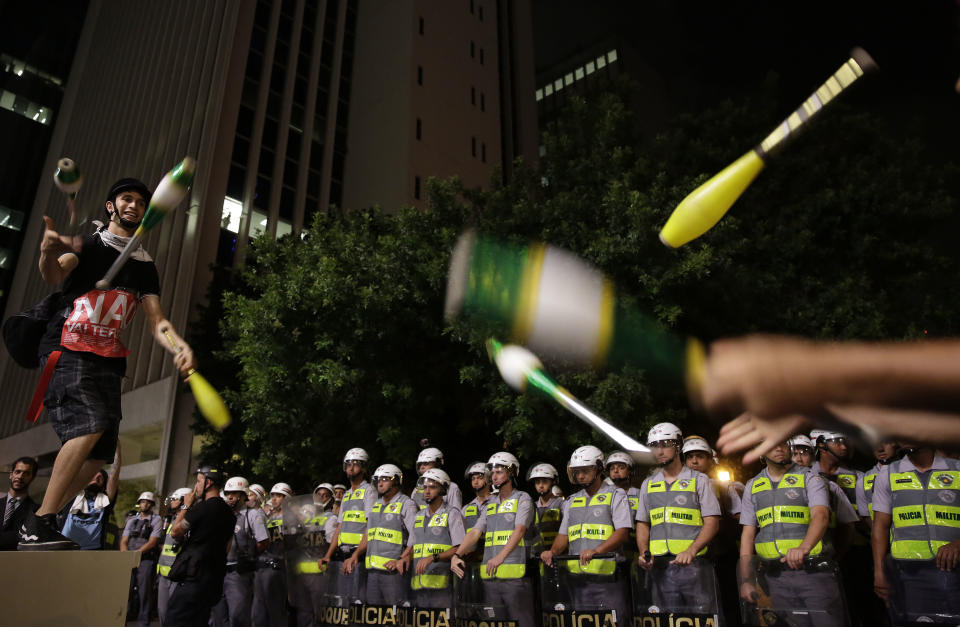 Demostrators surrounded by riot police juggle pins as they protest against money spent on the World Cup preparations in Sao Paulo, Brazil, Thursday, March 13, 2014. Thursday, Brazilian Sports Minister Aldo Rebelo guaranteed "the World Cup in Brazil will be the safest" in history even though widespread demonstrations are expected across the country to protest against corruption, poor public services and the billions of dollars being spent on the World Cup and 2016 Olympics in Rio de Janeiro. (AP Photo/Andre Penner)