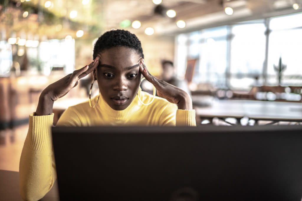 A woman looks frustrated as she looks at her laptop. 