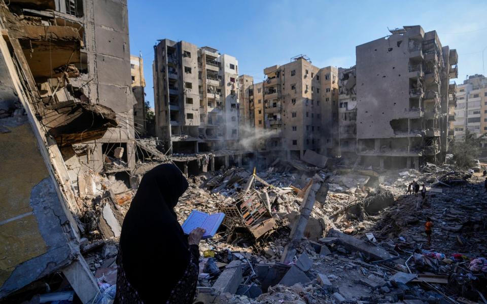 A woman reads the Quran at the site of the assassination of Hezbollah leader Hassan Nasrallah