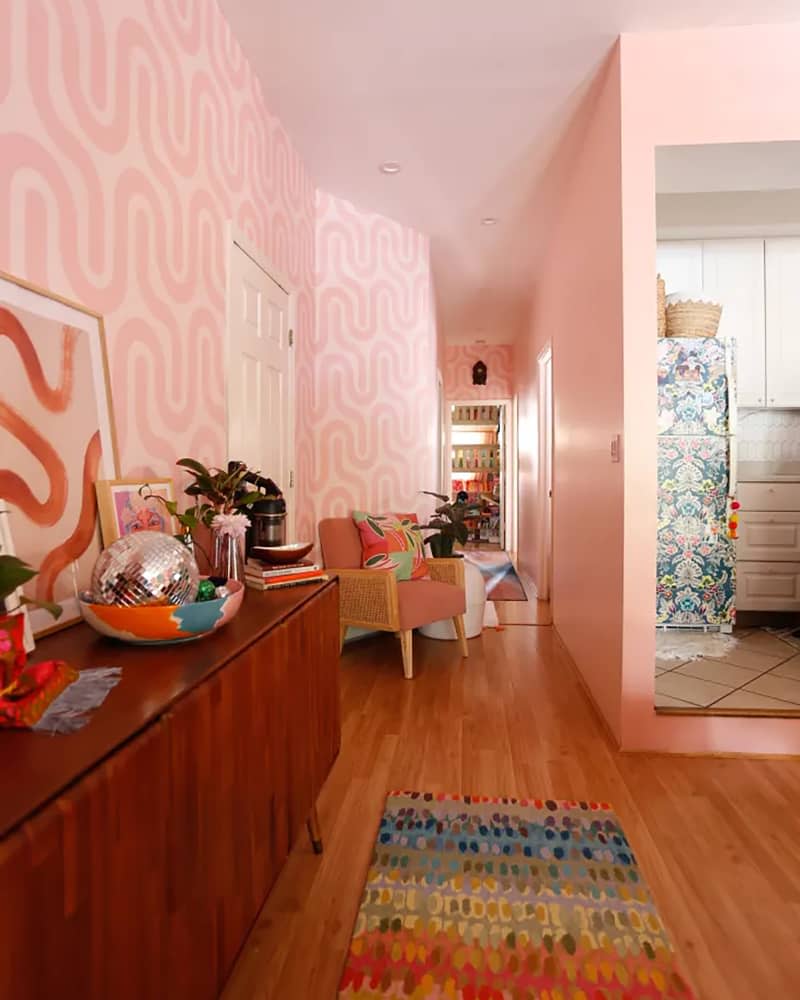 Pink hallway with patterned pink and white accent wall and lots of other color accents