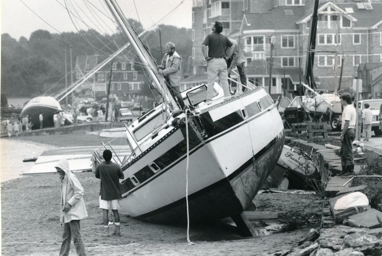 Workers remove the mast from a boat that washed ashore on the Jamestown waterfront during Hurricane Bob in August 1991, the last major hurricane to make landfall in Rhode Island.   [Michael J.B. Kelley/The Providence Journal, file]