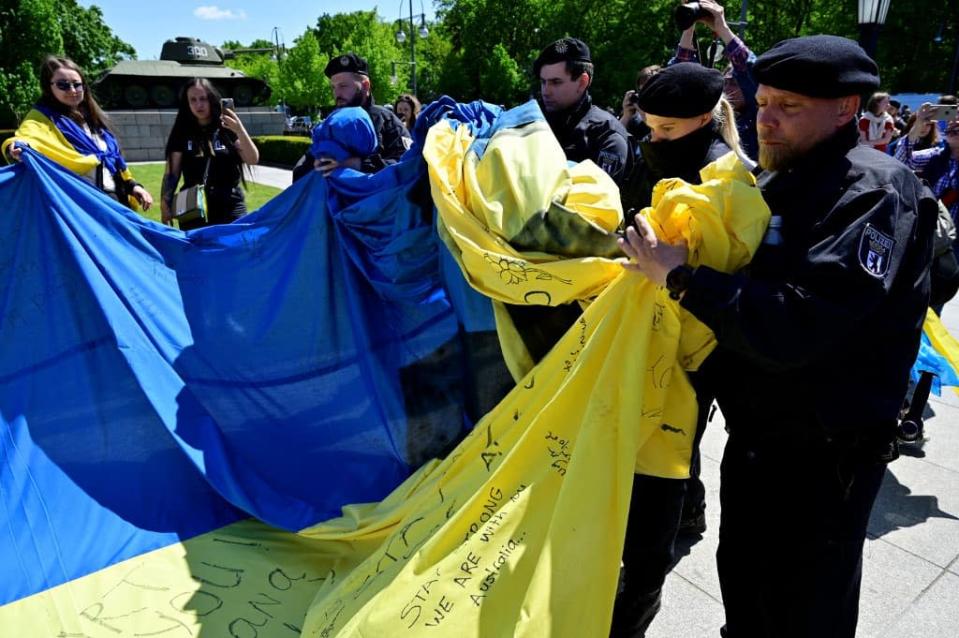 La police allemande en train de replier un drapeau ukrainien ce dimanche 8-Mai &#xe0; Berlin. - John MACDOUGALL