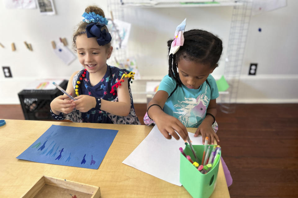 In this undated photo provided by The Hechinger Report, two girls draw during an activity at Early Partners, a child care center in New Orleans. City Seats, a program that pays for families in the parish to receive child care, funds more than a dozen child care slots at Early Partners. (Ariel Gilreath/The Hechinger Report via AP)