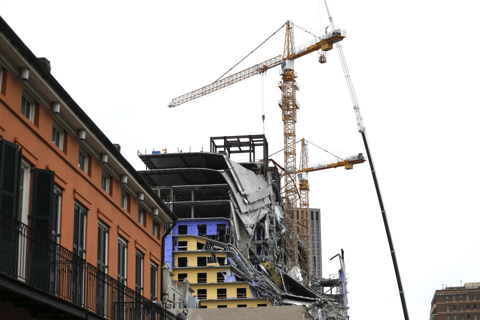 Workers in a bucket hoisted by a crane begin the process of preparing the two unstable cranes for implosion at the collapse site of the Hard Rock Hotel, which underwent a partial, major collapse while under construction last Sat., Oct., 12, in New Orleans, Friday, Oct. 18, 2019. Plans have been pushed back a day to bring down two giant, unstable construction cranes in a series of controlled explosions before they can topple onto historic New Orleans buildings, the city's fire chief said Friday, noting the risky work involved in placing explosive on the towers. (AP Photo/Gerald Herbert)