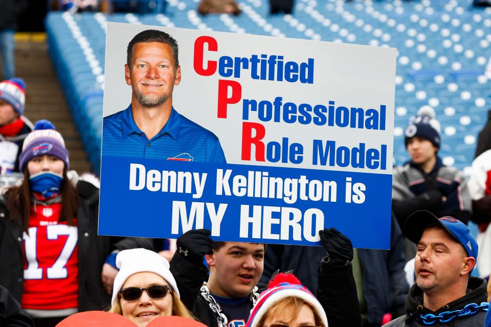 A fan holds sign bearing the likeness of Buffalo Bills trainer Denny Kellington during practices before an NFL football game against the New England Patriots, Sunday, Jan. 8, 2023, in Orchard Park, N.Y. Kellington was instrumental in responding to Hamlin's emergency. Hamlin remains hospitalized after suffering a catastrophic on-field collapse in the team's previous game against the Cincinnati Bengals. (AP Photo/Jeffrey T. Barnes)