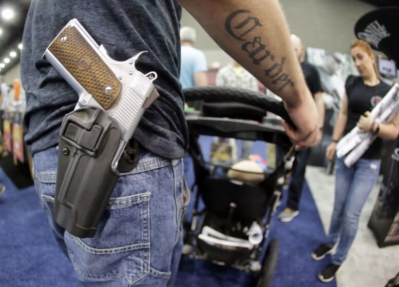 FILE - In this May 21, 2016, file photo, Donald Carder wears his handgun in a holster as he pushes his son, Waylon, in a stroller at the National Rifle Association convention in Louisville, Ky. Attendees at the convention are permitted to carry firearms under Kentucky's open carry law. (AP Photo/Mark Humphrey, File)