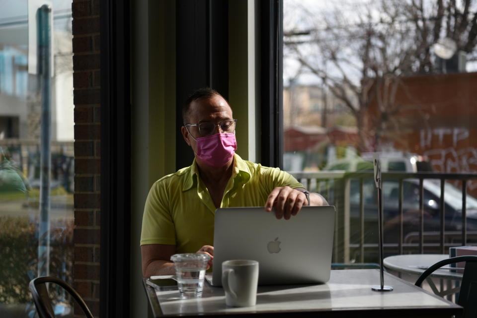 A man wearing a mask works on his laptop as the state of Texas prepares to lift its mask mandate and reopen businesses to full capacity during the coronavirus disease (COVID-19) pandemic in Houston, Texas, U.S., March 9, 2021. REUTERS/Callaghan O'Hare