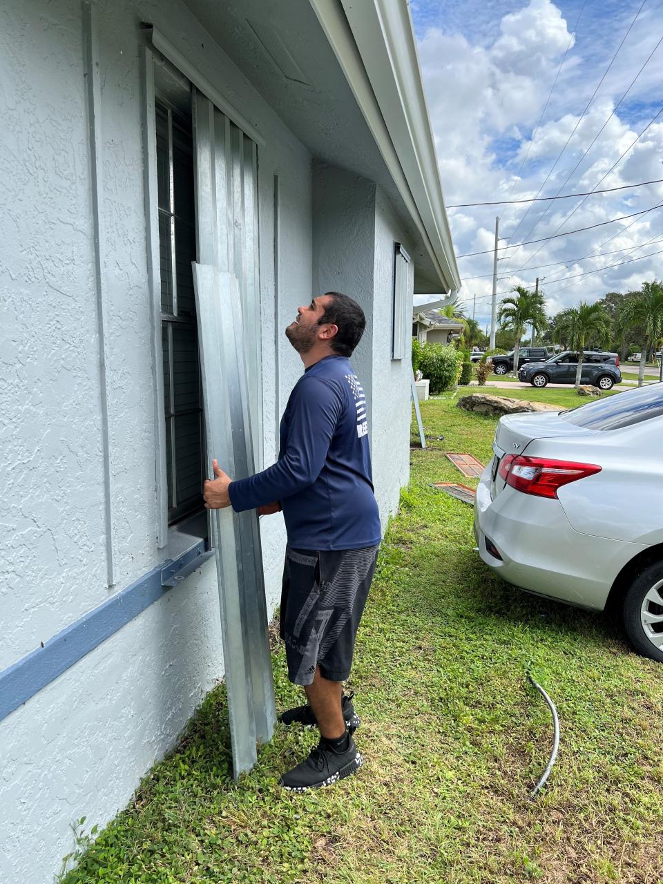 In preparation for Hurricane Ian, Aaron Landeros puts up shutters at his brothers home in Cape Coral.