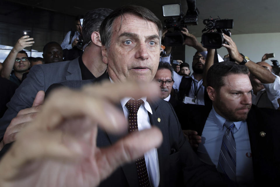 In this Nov. 13, 2018 photo, Brazil's President-elect Jair Bolsonaro is surrounded by the press and supporters as he leaves the Supreme Labor Court in Brasilia, Brazil. Bolsonaro, a far-right former army captain, assumes office Jan. 1. (AP Photo/Eraldo Peres)