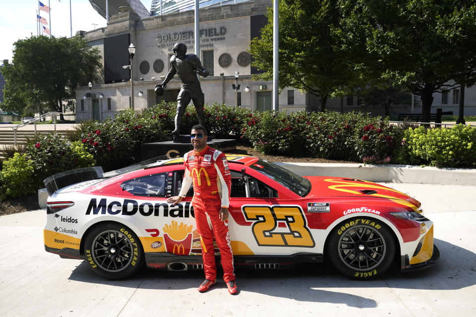 NASCAR driver Bubba Wallace poses for photos outside Soldier Field, near the Walter Payton statue, Tuesday, July 19, 2022, in Chicago during a promotional visit to announce a Cup Series street race in the city, to be held July 2, 2023. (AP Photo/Charles Rex Arbogast)