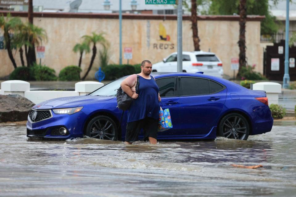 A man crosses a flooded intersection as Tropical Storm Hilary heads north into Palm Springs, California (AFP via Getty Images)