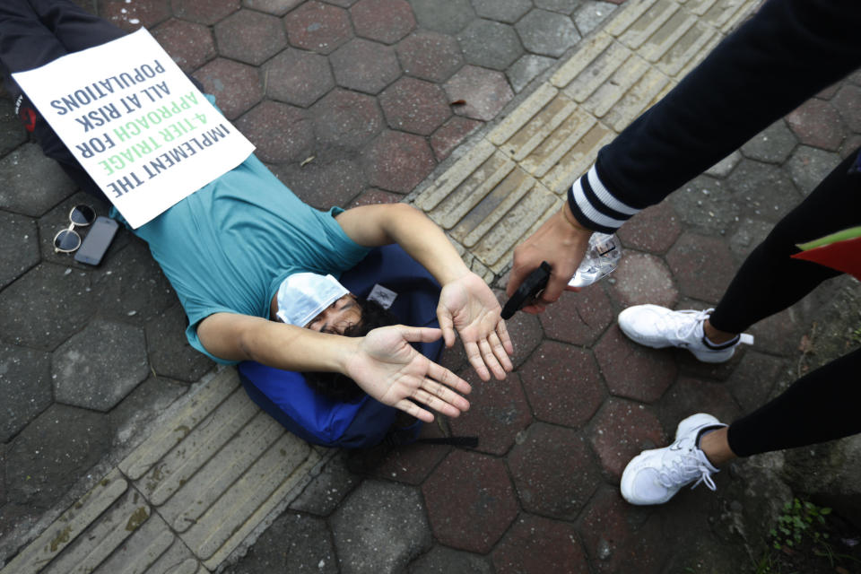 A protester uses a hand sanitizer as he lies on the ground demanding better handling of the COVID-19 pandemic in Kathmandu, Nepal, Saturday, June 20, 2020. Hundreds participated demanding increased testing and protesting alleged corruption by government officials while purchasing equipment and testing kits. (AP Photo/Niranjan Shrestha)