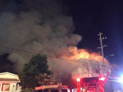 Flames rise from the top of a warehouse, which caught fire during a dance party in Oakland, California, U.S. December 3, 2016. Seung Lee/Handout via Reuters