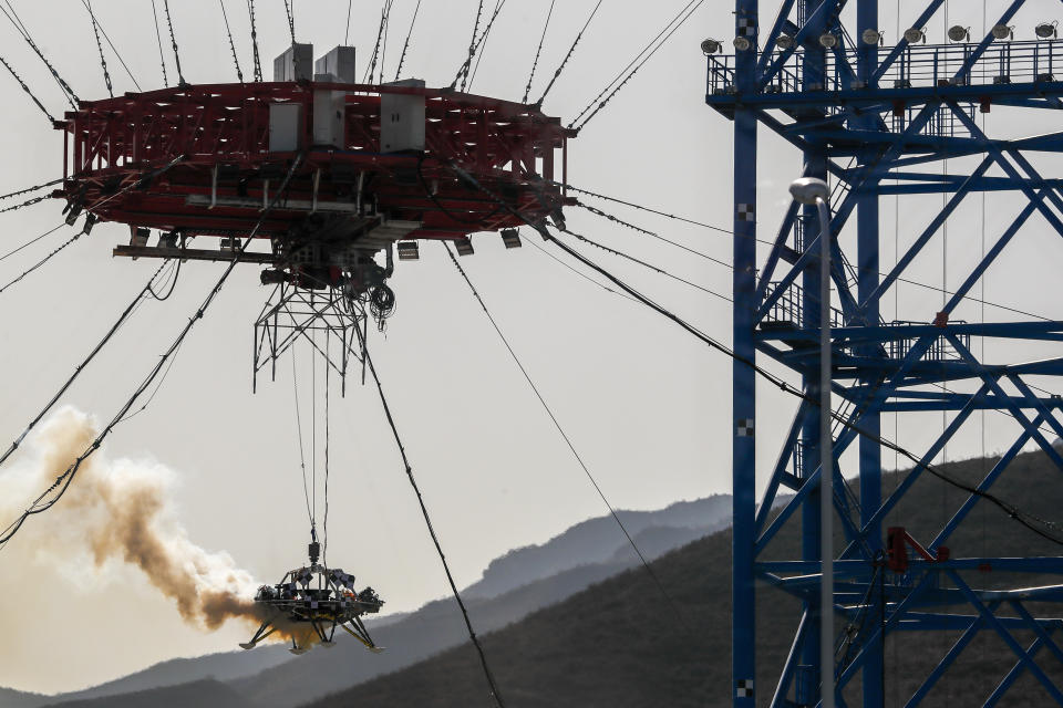 A lander is lifted during a test of hovering, obstacle avoidance and deceleration capabilities at a facility in Huailai in China's Hebei province, Thursday, Nov. 14, 2019. China has invited international observers to the test of its Mars lander as it pushes for inclusion in more global space projects. Thursday's test was conducted at a site outside Beijing simulating conditions on the Red Planet, where the pull of gravity is about one-third that of Earth.(AP Photo/Andy Wong)