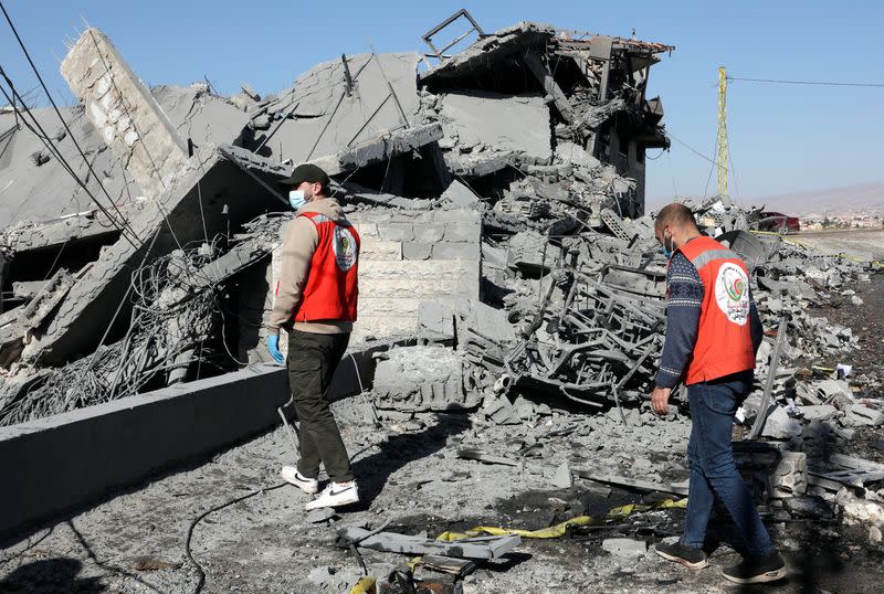 Civil defence members walk on the rubble of a damaged site that was hit by a strike, in Douris