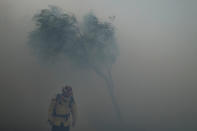 A firefighter braves gusty winds as heavy smoke from the Silverado Fire fills the air, Monday, Oct. 26, 2020, in Irvine, Calif. A fast-moving wildfire forced evacuation orders for 60,000 people in Southern California on Monday as powerful winds across the state prompted power to be cut to hundreds of thousands to prevent utility equipment from sparking new blazes. (AP Photo/Jae C. Hong)